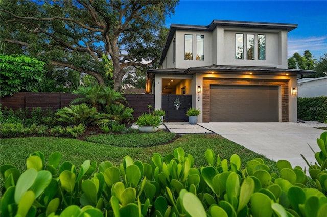modern home with stucco siding, driveway, fence, and a garage