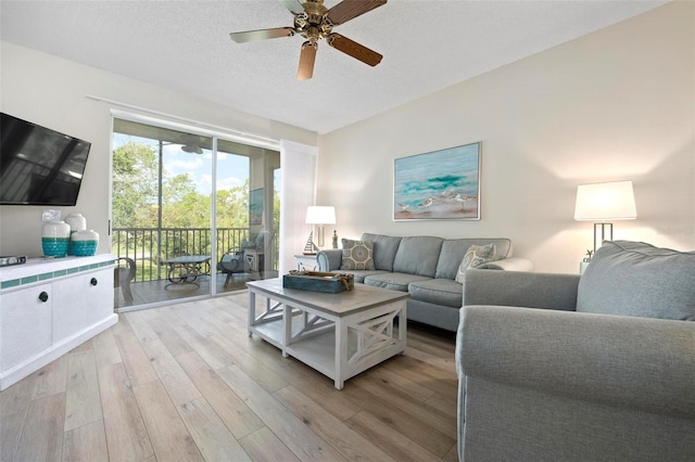 living area with a textured ceiling, ceiling fan, and light wood finished floors