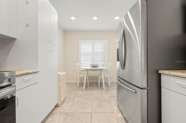 kitchen with stainless steel fridge with ice dispenser, white cabinets, baseboards, light stone counters, and recessed lighting