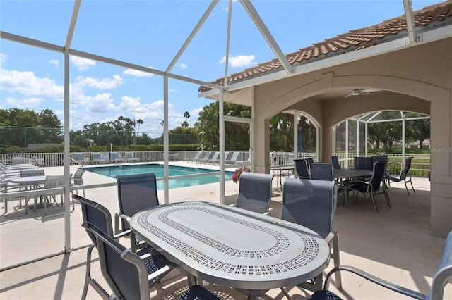 community pool featuring ceiling fan, a lanai, outdoor dining area, a patio area, and fence