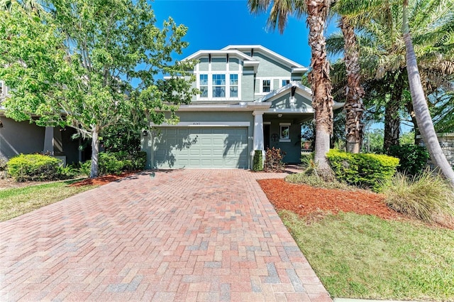 craftsman inspired home with an attached garage, decorative driveway, and stucco siding
