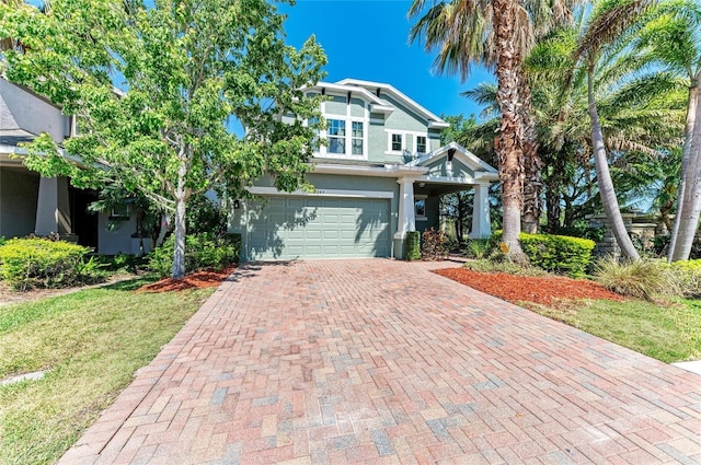 view of front of house featuring a garage, decorative driveway, stucco siding, and a front yard