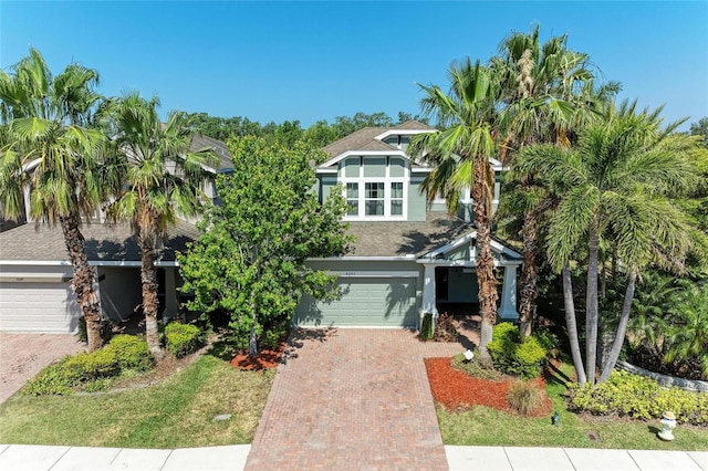 view of front of home featuring stucco siding, decorative driveway, roof with shingles, and a garage