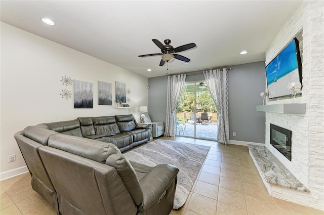 living area with a ceiling fan, baseboards, light tile patterned flooring, and a fireplace