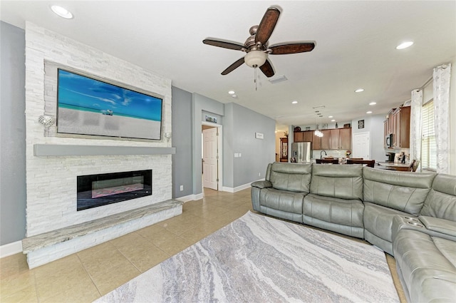 living area featuring a fireplace, a ceiling fan, baseboards, recessed lighting, and light tile patterned floors