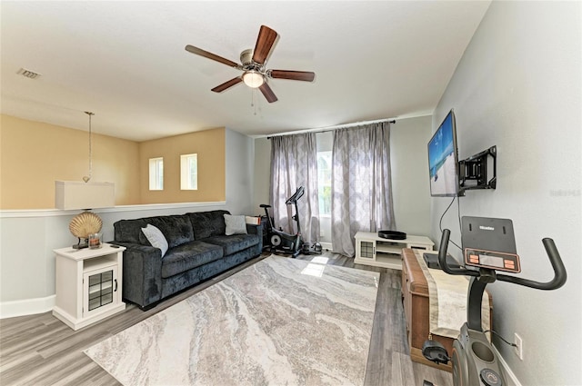 living area featuring baseboards, plenty of natural light, a ceiling fan, and wood finished floors