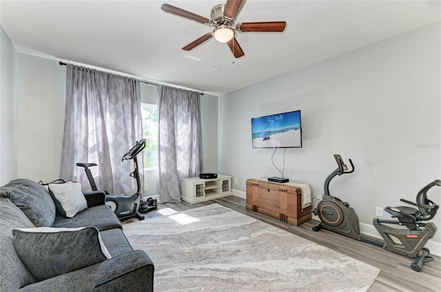 living area featuring baseboards, ceiling fan, and wood finished floors