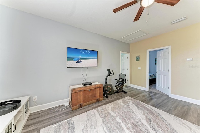 living room with ceiling fan, attic access, visible vents, wood finished floors, and baseboards