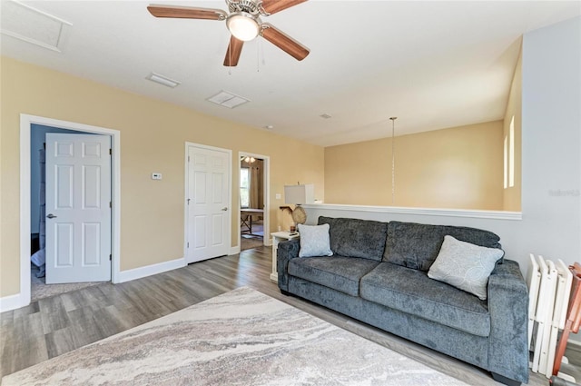 living area featuring baseboards, ceiling fan, visible vents, and wood finished floors