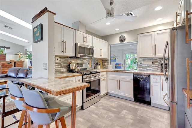 519 Bayview Ave, Osprey, FL 34229 - kitchen with stainless steel appliances, a sink, light countertops, a ceiling fan, and a peninsula