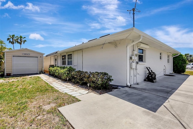 519 Bayview Ave, Osprey, FL 34229 - view of side of home with a patio area, stucco siding, a garage, a lawn, and an outbuilding