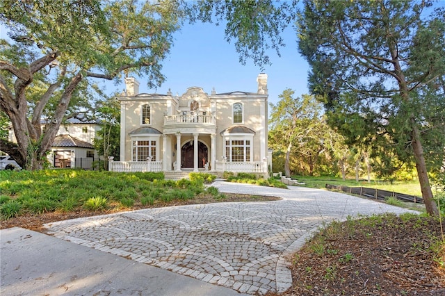 view of front of house with driveway, covered porch, a balcony, and fence private yard