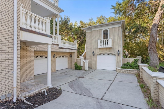 view of property exterior featuring brick siding, driveway, a garage, and a balcony