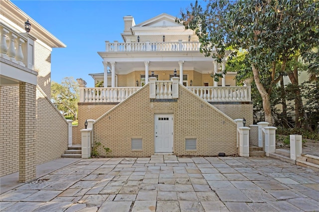 rear view of house with a patio, stairway, and brick siding