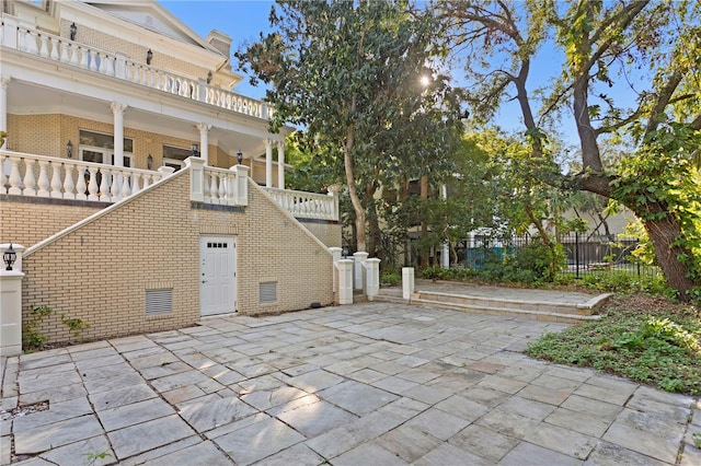 view of patio featuring fence and stairs
