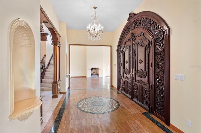 foyer featuring baseboards, stairway, arched walkways, and an inviting chandelier
