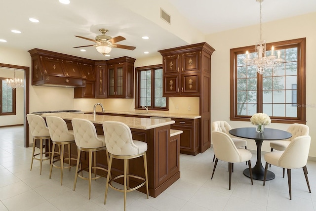 kitchen with a breakfast bar area, recessed lighting, visible vents, and ceiling fan with notable chandelier