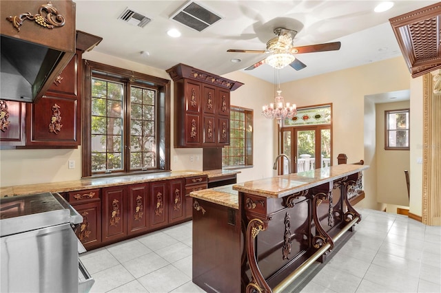kitchen featuring plenty of natural light, visible vents, dark brown cabinets, and ceiling fan with notable chandelier