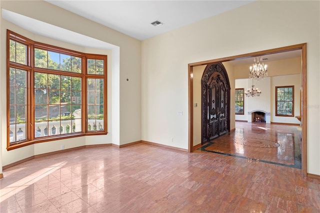 foyer entrance with baseboards, visible vents, an inviting chandelier, and a fireplace