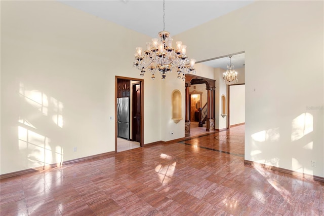 unfurnished dining area featuring arched walkways, a chandelier, and baseboards