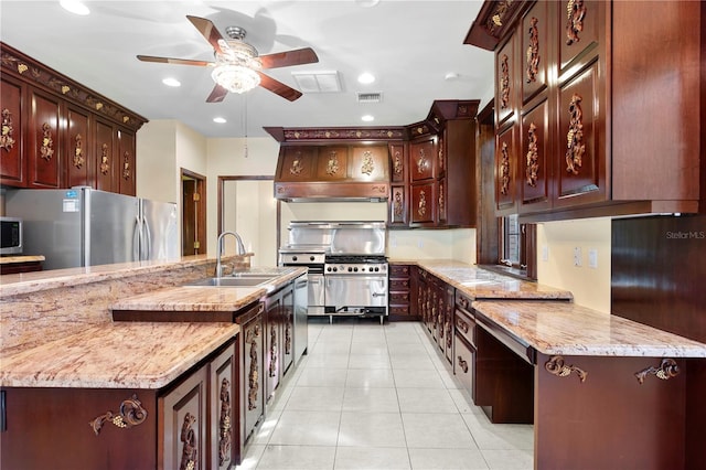 kitchen featuring light stone countertops, freestanding refrigerator, light tile patterned floors, ceiling fan, and a sink