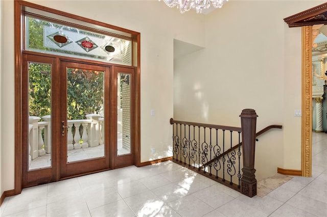 tiled foyer with a notable chandelier and baseboards