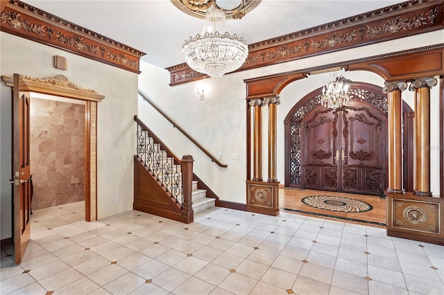 foyer entrance with light tile patterned floors, an inviting chandelier, and decorative columns