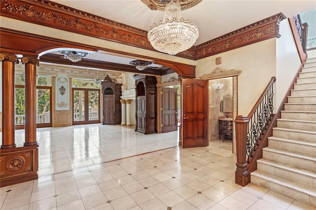 tiled entrance foyer with decorative columns, a notable chandelier, ornamental molding, and arched walkways