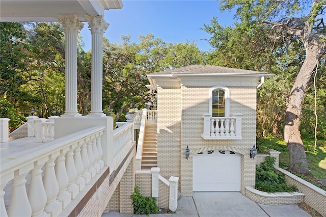view of home's exterior featuring concrete driveway, stairway, an attached garage, and brick siding