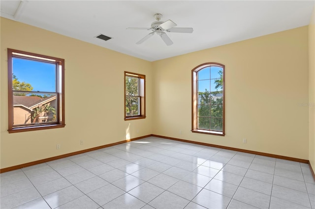 spare room featuring baseboards, visible vents, a ceiling fan, and light tile patterned flooring