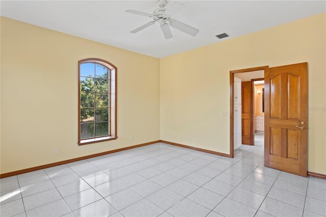 unfurnished room featuring light tile patterned flooring, visible vents, a ceiling fan, and baseboards