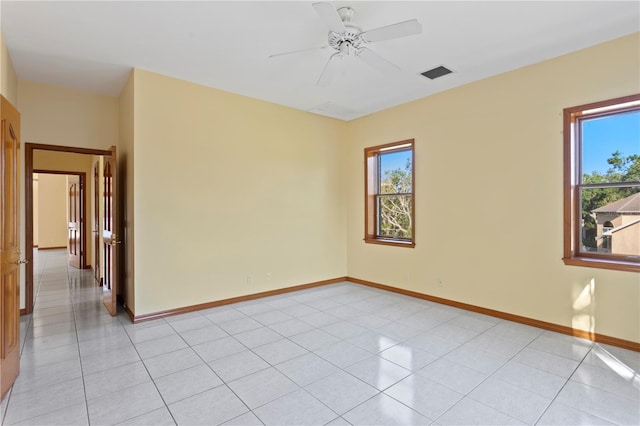 unfurnished room featuring a wealth of natural light, ceiling fan, visible vents, and baseboards