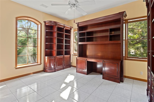 unfurnished office with light tile patterned floors, visible vents, ceiling fan, and baseboards