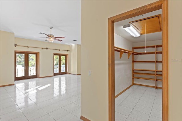 interior space featuring light tile patterned floors, attic access, a ceiling fan, and french doors