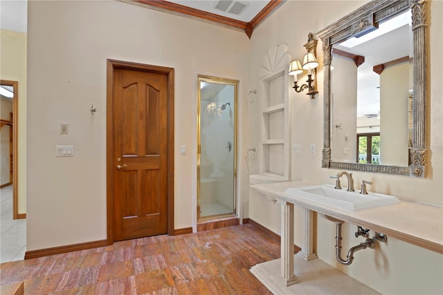 bathroom featuring a sink, a shower stall, visible vents, baseboards, and ornamental molding