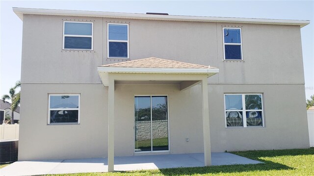 215 63rd Dr E, Bradenton, FL 34203 - back of property featuring a shingled roof, a patio area, a yard, cooling unit, and stucco siding