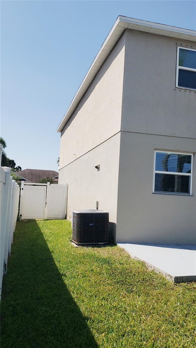 215 63rd Dr E, Bradenton, FL 34203 - view of side of home with a fenced backyard, cooling unit, a lawn, and stucco siding