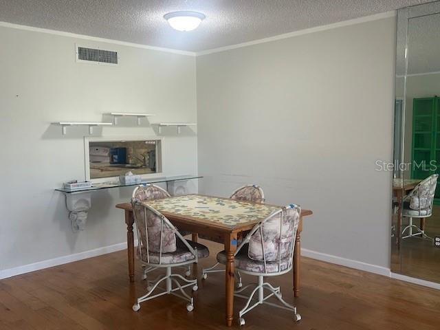 7461 W Country Club Dr N Unit 201, Sarasota, FL 34243 - dining area featuring wood finished floors, ornamental molding, a textured ceiling, and baseboards