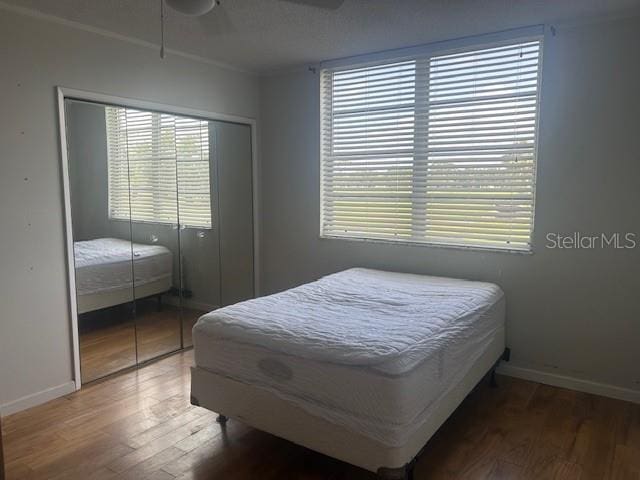 7461 W Country Club Dr N Unit 201, Sarasota, FL 34243 - bedroom with wood finished floors, a closet, multiple windows, and baseboards