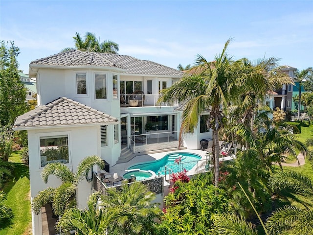 7118 Hawks Harbor Cir, Bradenton, FL 34207 - back of house with a balcony, stucco siding, a patio area, a pool with connected hot tub, and a tile roof