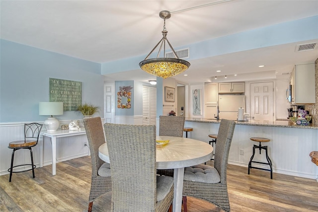 5920 Midnight Pass Rd Unit 406, Sarasota, FL 34242 - dining area featuring light wood-type flooring and a wainscoted wall