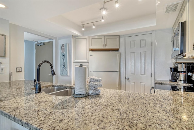5920 Midnight Pass Rd Unit 406, Sarasota, FL 34242 - kitchen with freestanding refrigerator, a sink, stainless steel microwave, light stone counters, and a tray ceiling