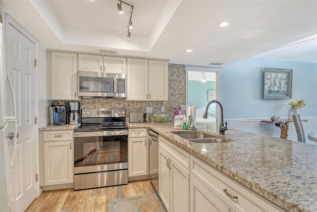 5920 Midnight Pass Rd Unit 406, Sarasota, FL 34242 - kitchen with stainless steel appliances, a sink, a tray ceiling, light stone counters, and light wood-style flooring