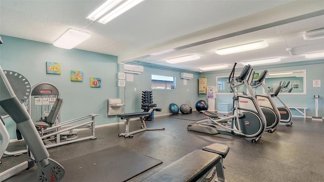 5920 Midnight Pass Rd Unit 406, Sarasota, FL 34242 - workout area with a wall mounted air conditioner, a textured ceiling, a wall mounted AC, and baseboards