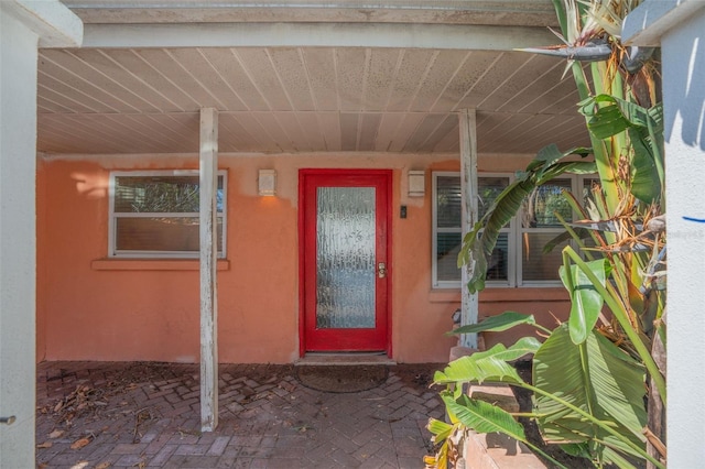 property entrance featuring a porch and stucco siding