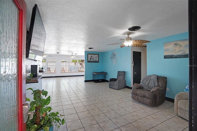 interior space featuring ceiling fan, baseboards, a textured ceiling, and light tile patterned floors