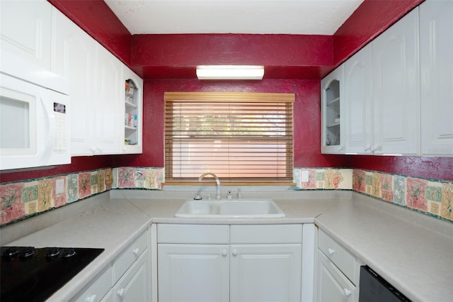 kitchen featuring white cabinets, white microwave, black electric stovetop, and a sink