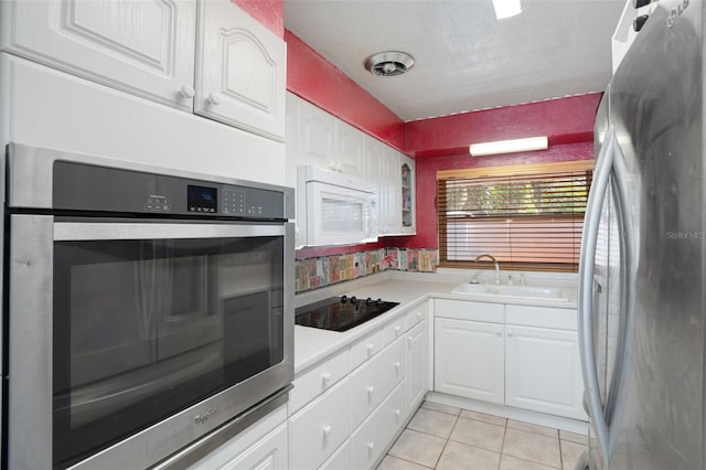 kitchen featuring a sink, light tile patterned floors, stainless steel appliances, light countertops, and white cabinets