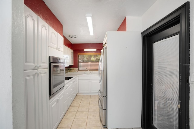 kitchen with stainless steel appliances, a sink, white cabinetry, light countertops, and light tile patterned floors