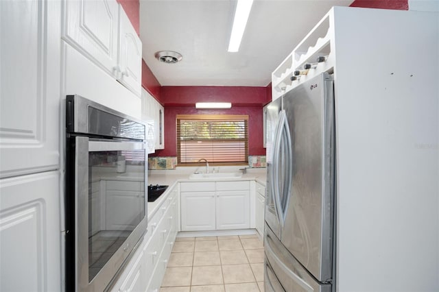 kitchen with stainless steel appliances, a sink, white cabinetry, and light tile patterned flooring